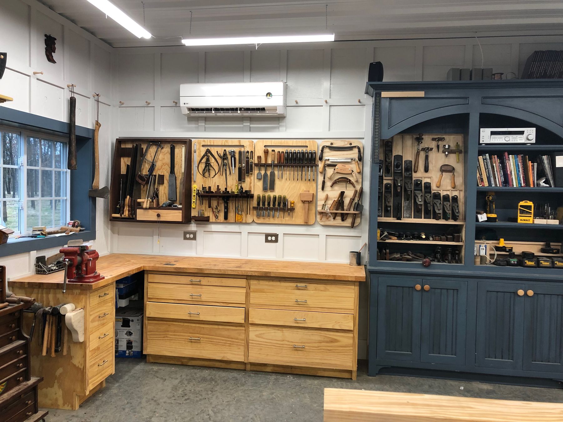 A hand-tool wall above maple drawers and blue cabinetry